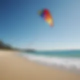 A vibrant, colorful kite soaring in a clear blue sky above a tranquil beach.