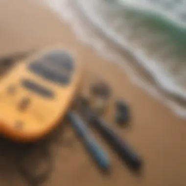 Close-up of essential paddle boarding gear laid out on a sandy beach